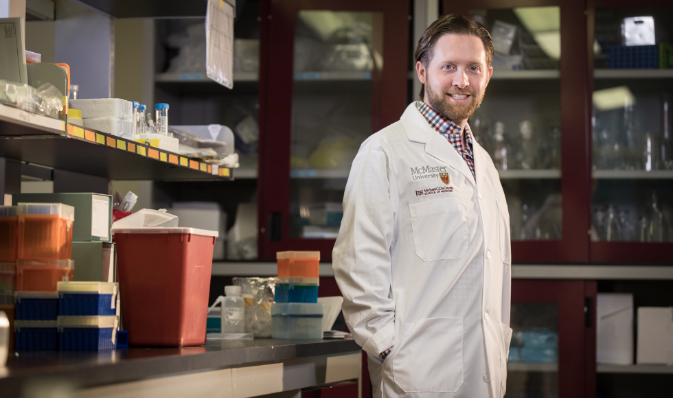 Man in lab coat stands in workspace.