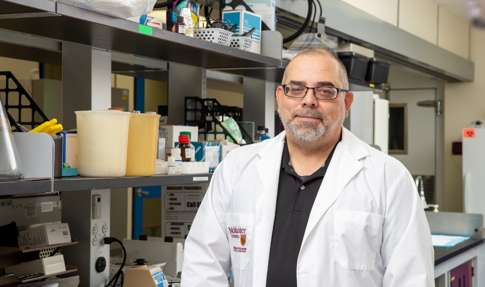 A man in a lab coat sits in front 