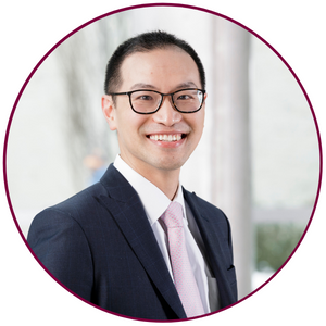 A headshot of Hsien Seow. He is wearing a white dress shirt, a pink tie and a black suit jacket. He is wearing glasses and smiling directly at the camera.