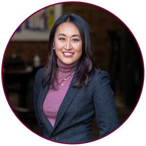 A headshot of Katrina Choe. She is wearing a mauve shirt and grey blazer. She is smiling directly at the camera.