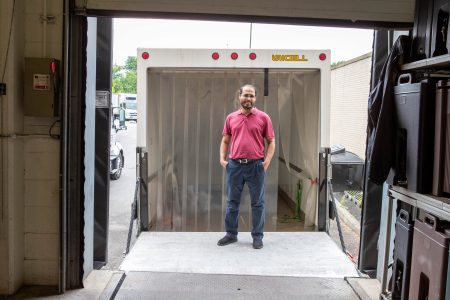 Elkafi Hassini poses in front of a transport truck waiting in a loading dock