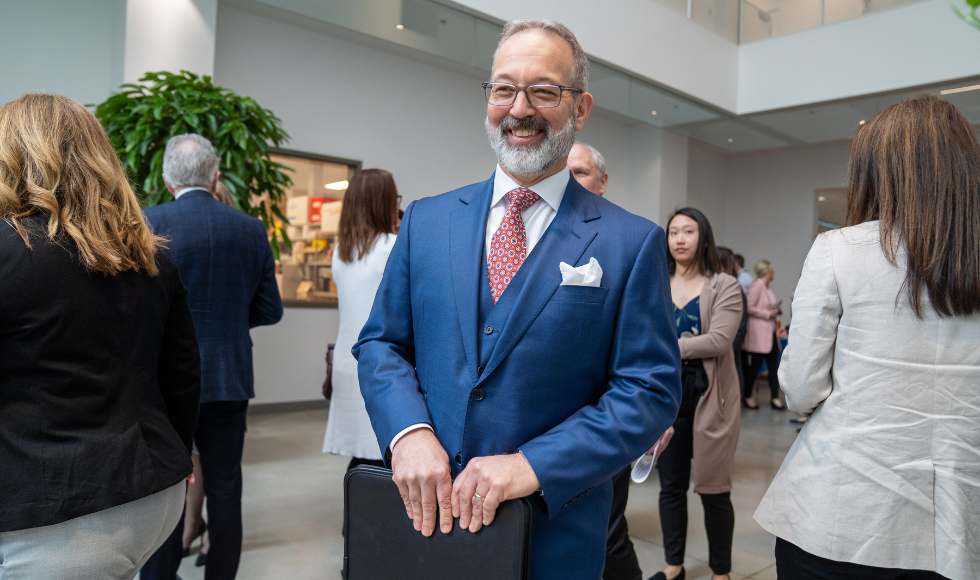 John Valliant wearing a blue suit, smiling 