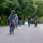 A group of students ride their bicycles on a paved trail in Hamilton.