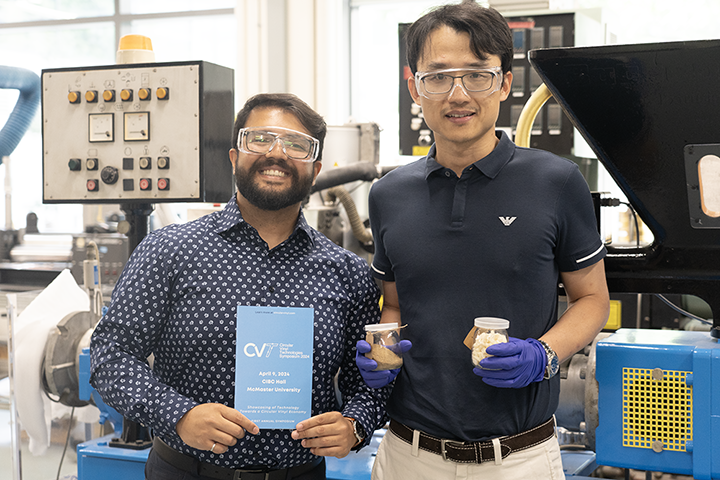 Kushal Panchal and Li Xi standing in a laboratory setting. Both are wearing goggles over their glasses. 