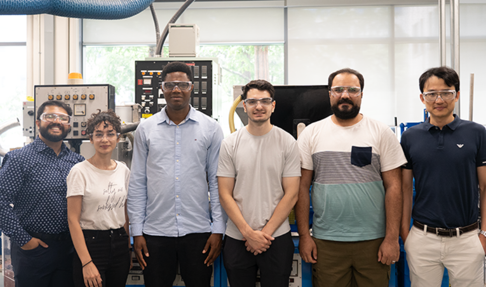 Six people standing posing for a photo. They all have protective eye wear on. 