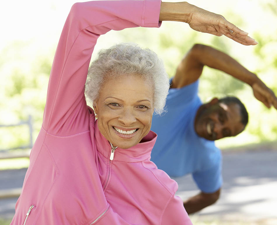 Senior African American couple stretching in the park