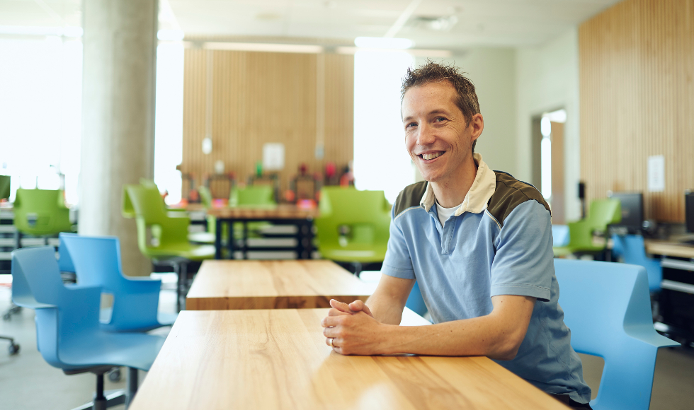 Photo of engineering professor Colin McDonald sitting at a table and smiling