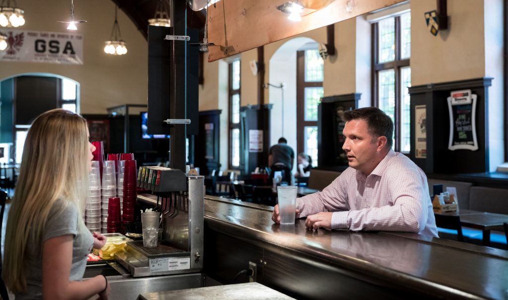 A bartender and a customer talk at a bar. The customer is Aaron Schat, a DeGroote School of Business associate professor who studies the way customers treat front-line service workers. Photo by Sarah Janes