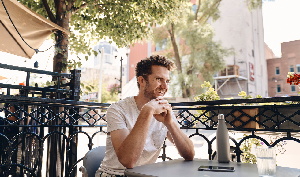 A man sits at a table at an outdoor patio