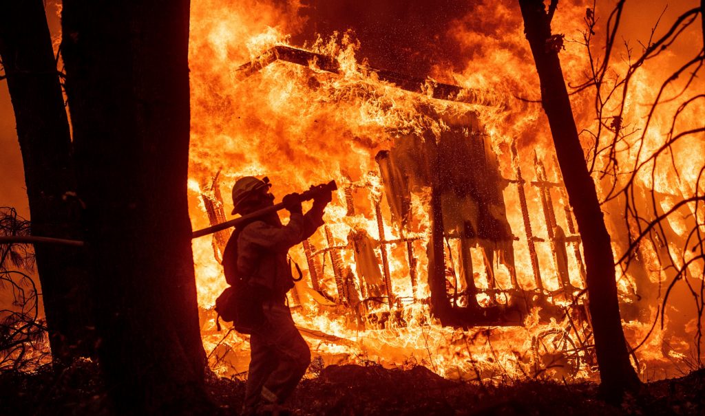 Firefighter Jose Corona sprays water as flames from the Camp Fire consume a home in Magalia, Calif., on Nov. 9, 2018. Photo by Noah Berger/AP