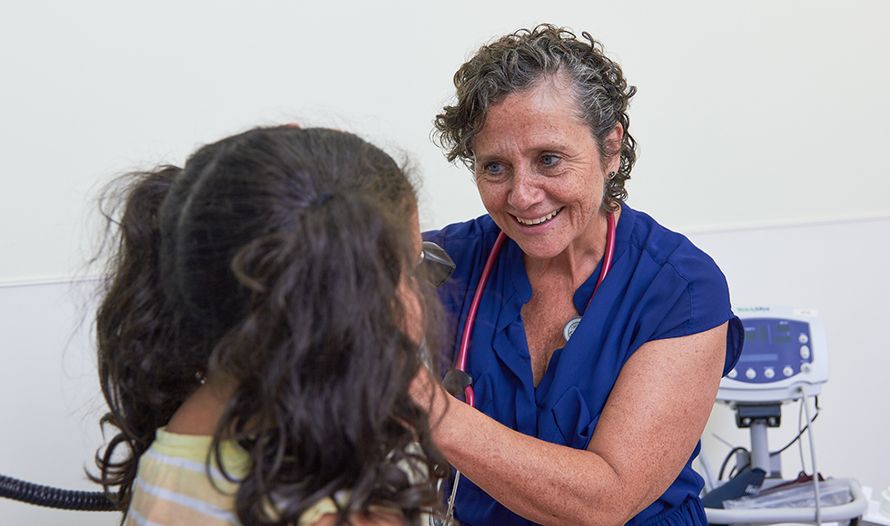 Katherine Morrison, researcher, treating a child in a clinic room.