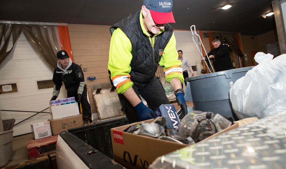 A man in a hat and safety gear loads a box of equipment