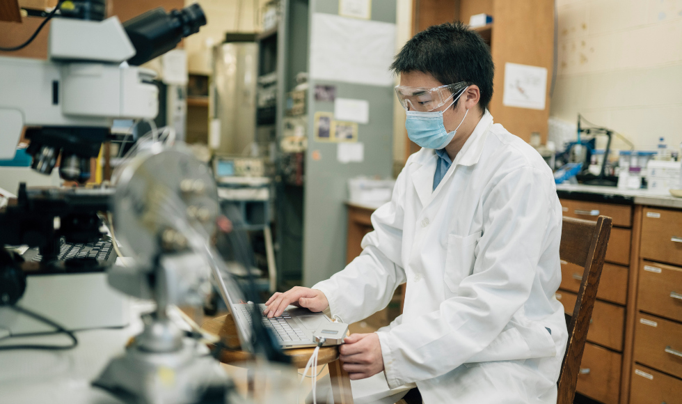 A man in a mask and safety goggles works in a lab