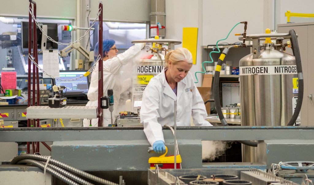 Two people working in a bright room with a lot of equipment — it's part of the nuclear reactor.