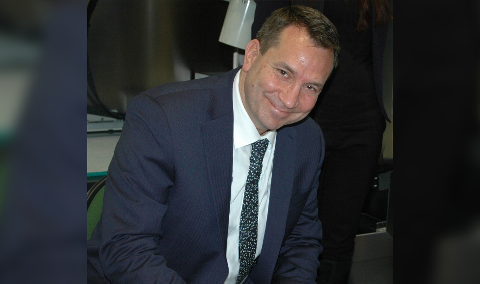 Dave Tucker in a suit and tie, smiling at the camera