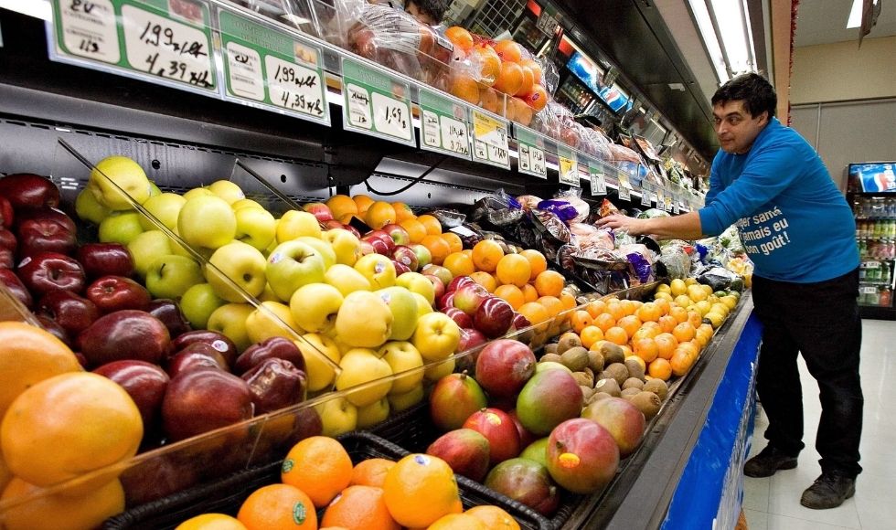 A grocery store worker stocks shelves of fruit