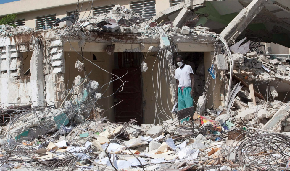 A masked person worker surrounded by rubbie and earthquake debris