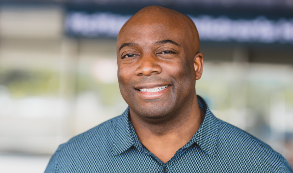 A headshot of Olufemi Ayeni. He is wearing a blue shirt and smiling at the camera.