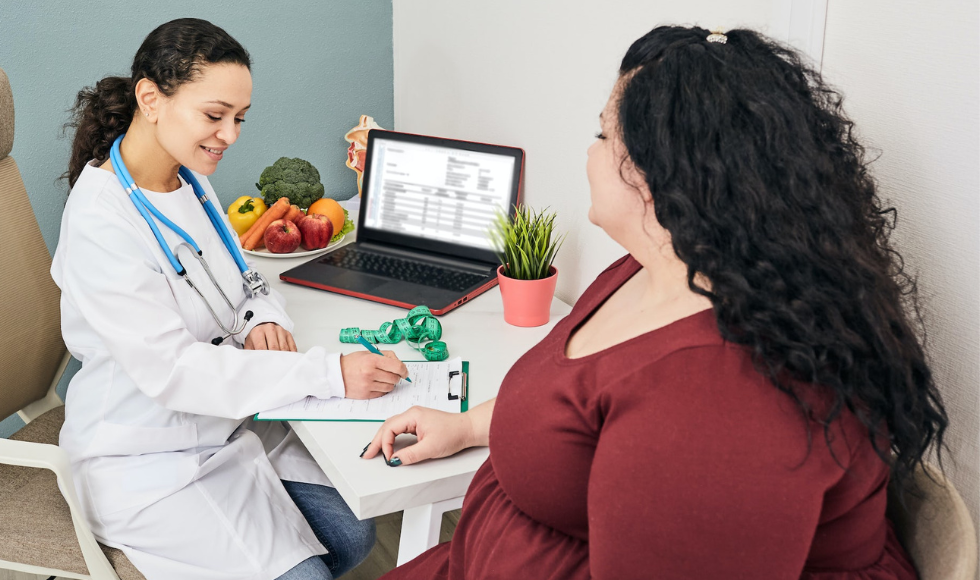 An overweight person seated near a medical professional with a stethescope