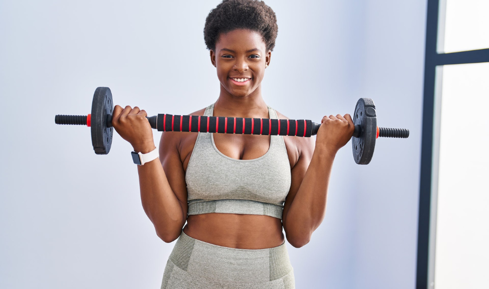 Woman standing with a weight in her hand, while smiling