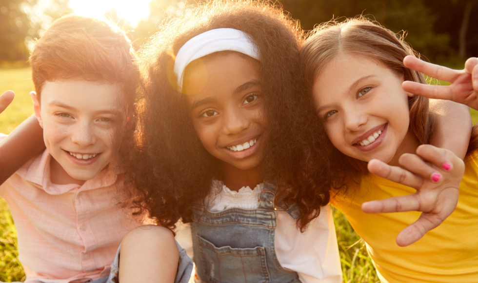 Image of three little kids hugging one another smiling