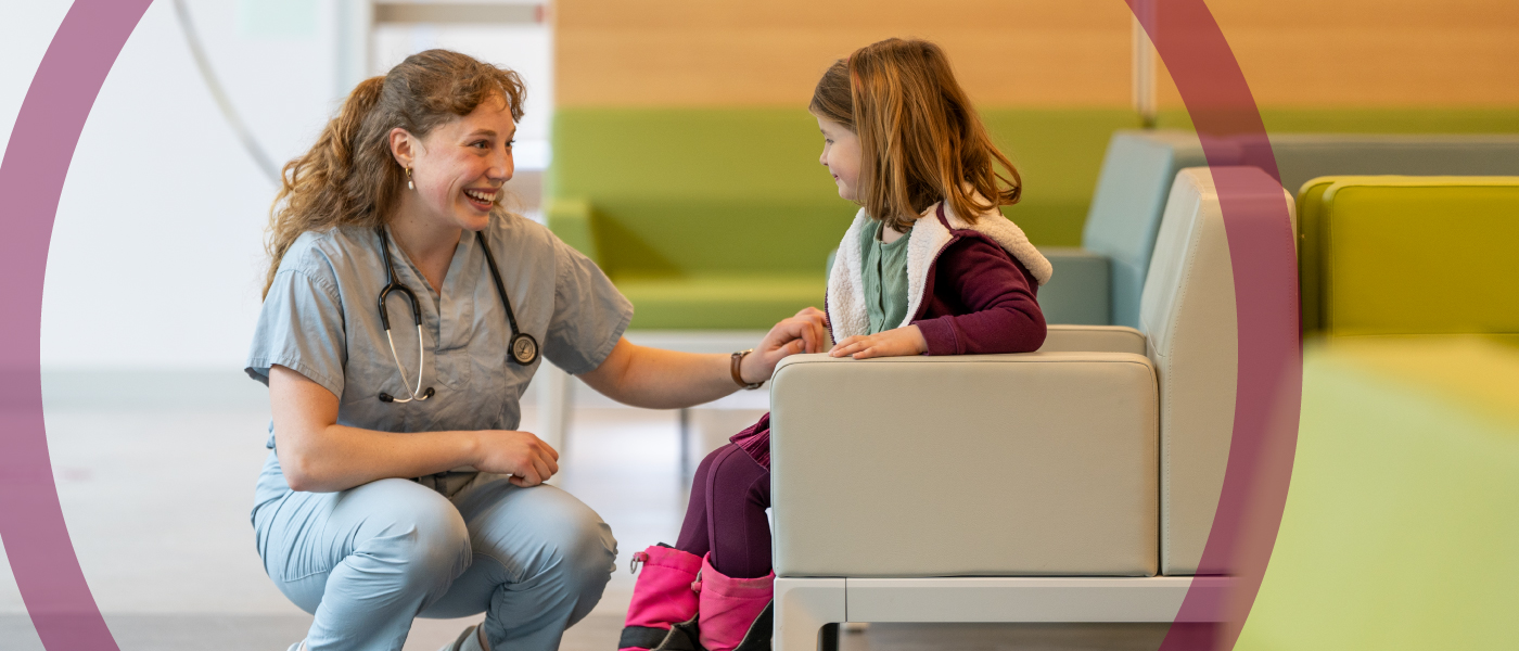 A medical student kneels and talks to a child patient.