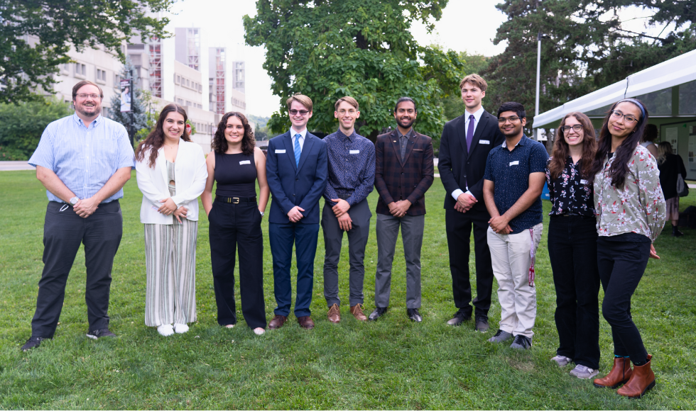 Ten people standing outdoors smiling at the camera