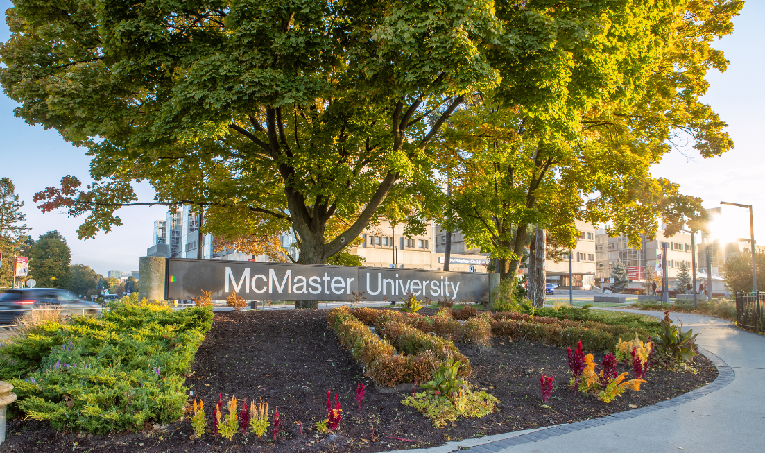 The McMaster University sign at the entrance to campus, on a sunlit fall day.