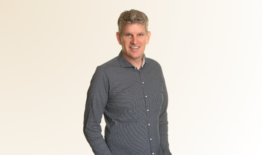 Waist up picture of Cameron Currie in a grey-blue shirt against a light backdrop