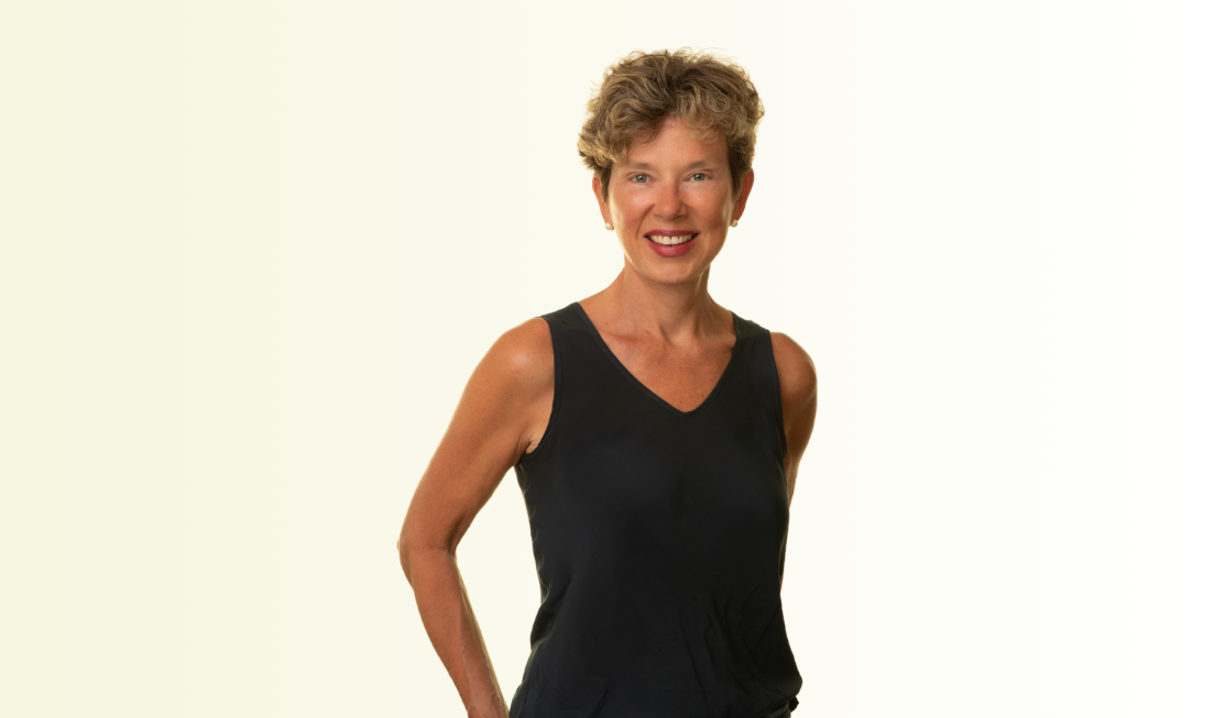 Deborah Cook wearing a black sleeveless top and smiling, against a light backdrop