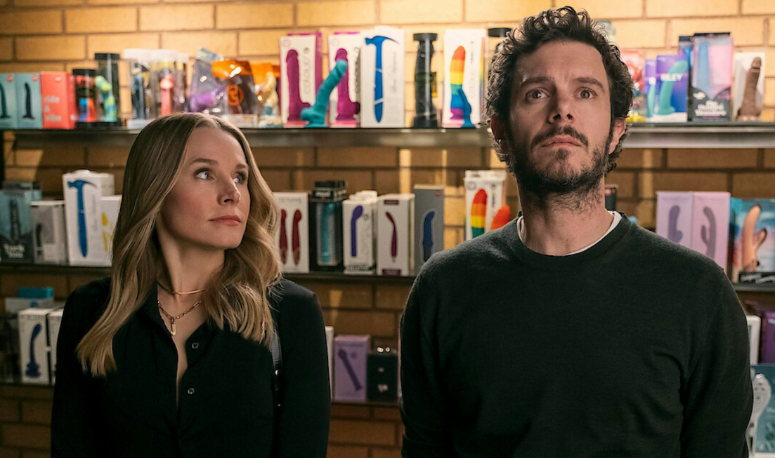 Scene from Nobody Wants This: A woman and man in front of a shelf of vibrators.