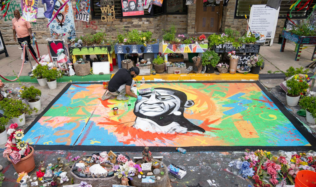 An artist working on a street mural of George Floyd.