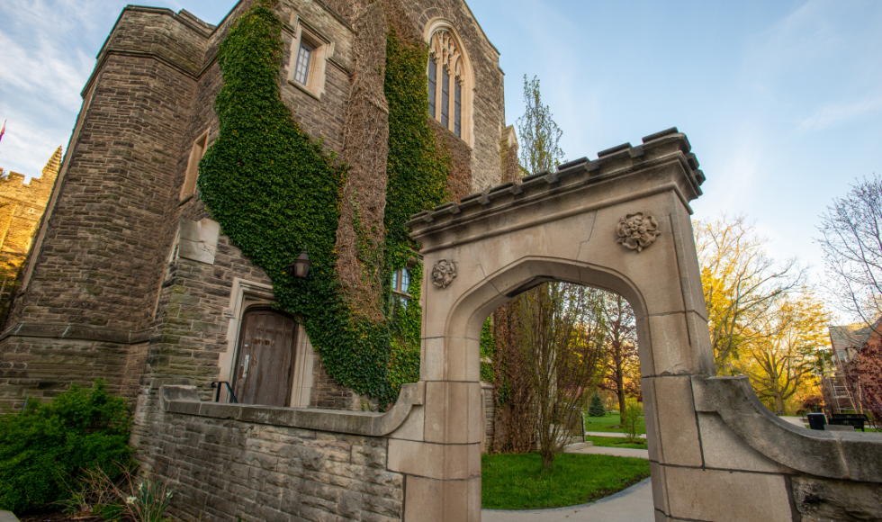 A stone archway and an ivy-covered stone building.