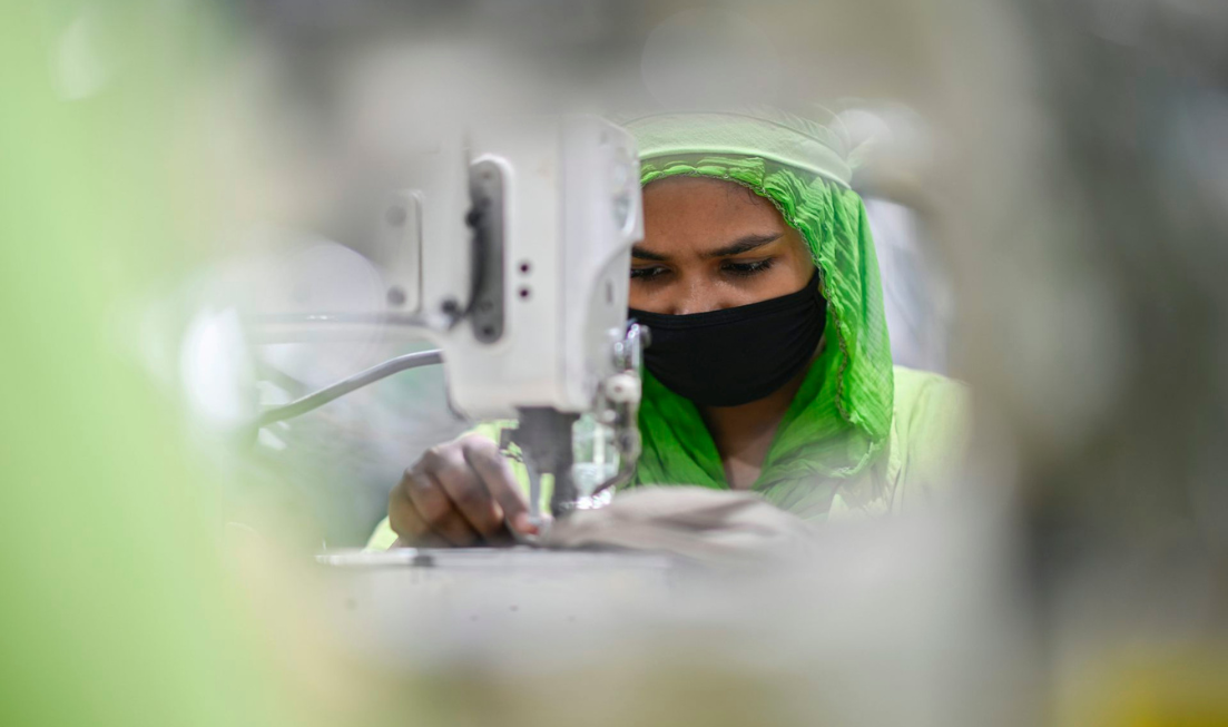 A woman stitches a garment at a factory
